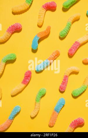 Gummy worms assorted candies on bright yellow background, top view Stock Photo