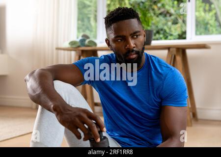 African american man sitting on mat at home Stock Photo