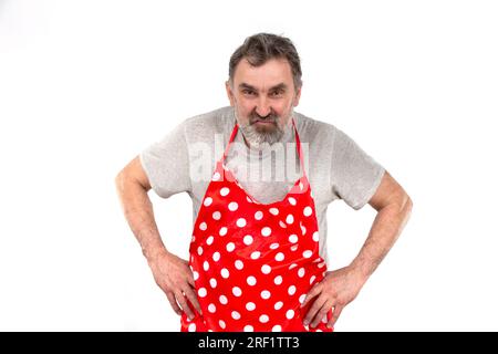 An elderly bearded man in a red polka-dot culinary apron on a white background. Stock Photo