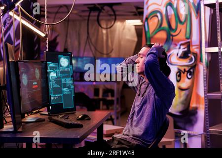 Upset hacker unsuccessfully hacking server while breaking law and doing illegal activity. Disappointed criminal holding head while getting access denied message on computer screen Stock Photo