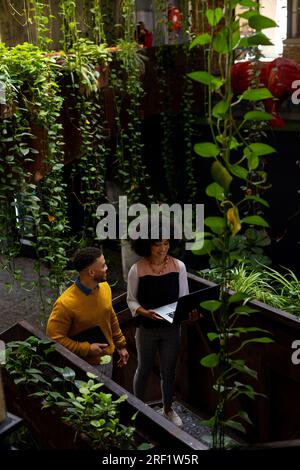 Happy diverse businesspeople discussing over a laptop on the stairs at office, copy space Stock Photo