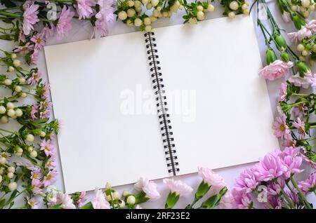 Empty white notebook and pencil with pink flowers on white background. Stock Photo