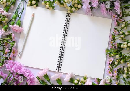 Empty white notebook with pink flowers on white background. Stock Photo