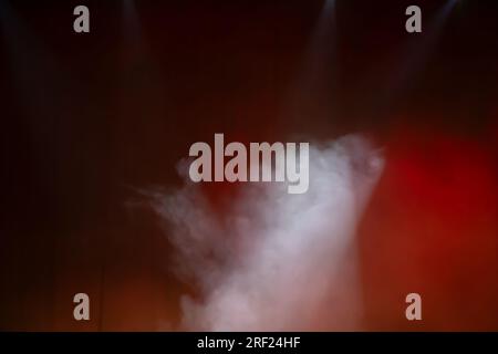 Red blurred background with puffs of white smoke. Stock Photo