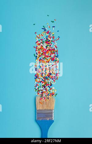 Star shaped sugar sprinkles and paint brush on blue background, art and creativity concept Stock Photo