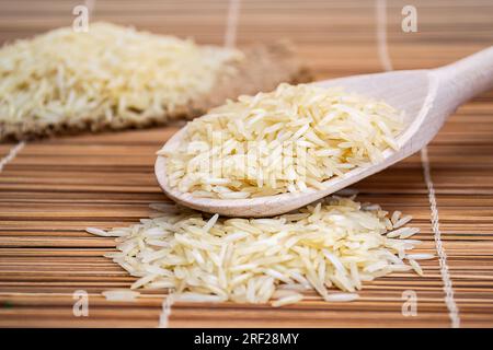 A wooden spoon filled with rice on top of a bamboo mat Stock Photo