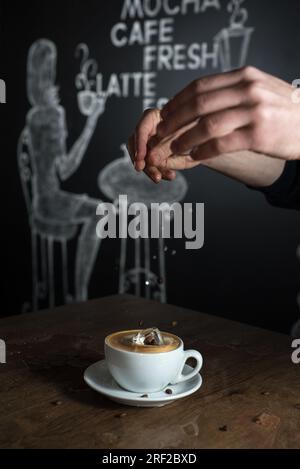 Cold coffee splash in a white cup on wooden table. Stock Photo