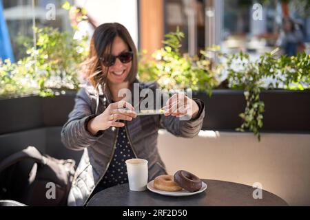 Woman having breakfast and using her mobile phone Stock Photo