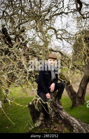 Portrait of man sitting on tree stump Stock Photo