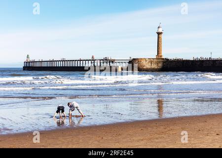 Kids playing on Whitby beach, kids playing in sand, Whitby, Yorkshire, UK, England, kids on beach, kids playing on beach, kids on sand, sandcastles Stock Photo