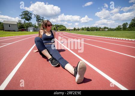 woman sits and relaxes on a running track while working out Stock Photo