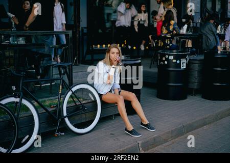 A young beautiful woman is drinking wine in a street restaurant. Stock Photo