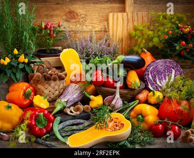 Assorted seasonal vegetables and fresh herbs on a rustic wooden table. Stock Photo