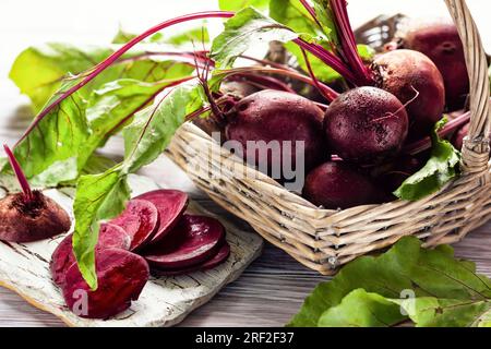 Fresh organic beetroot with green leaves in a basket on a  wnite wooden table. Stock Photo