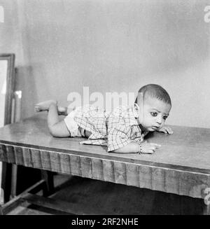 old vintage 1900s black and white picture studio portrait Indian baby lying on stomach India 1940s Stock Photo