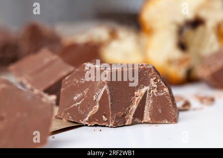 edible milk chocolate made from cocoa and sugar, pieces of chocolate randomly scattered on the table, broken and crumbled natural chocolate Stock Photo
