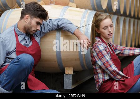 male and female workers asleep in wine cellar Stock Photo