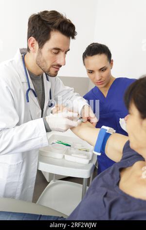 junior doctor watching blood pressure check on patient Stock Photo