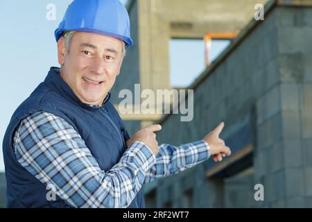 a builder pointing at wall Stock Photo