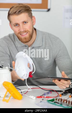 young energetic male tech or engineer repairs electronic equipment Stock Photo