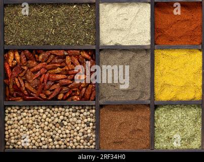 lots of various different spices in a framed dark wooden box seen from above Stock Photo