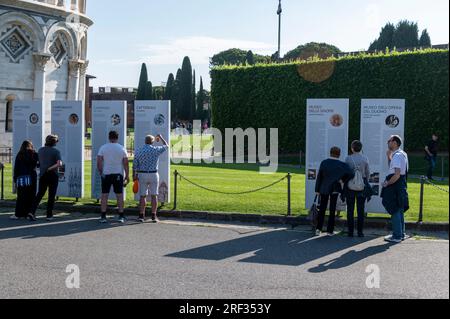 Tourists stopped to study the layout map of the Leaning Tower complex on the Plazza del Duomo in Pisa in the Tuscany region of Italy Stock Photo