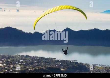 Paraglider flies in front of the blue lake Stock Photo