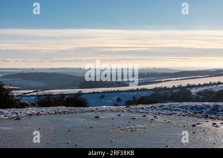 A frozen dew pond on Ditchling Beacon, with snow on the surrounding fields Stock Photo