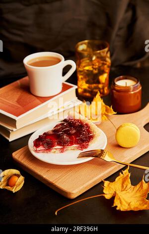 Cozy aesthetics home breakfast with cherry pie, macaroons and cup of coffee among candles. Hygge home aesthetic. Stock Photo
