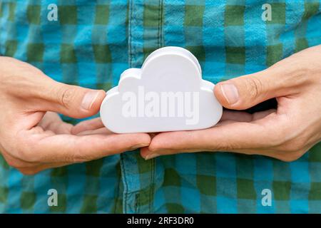 Man holding up a small white cloud object symbol in his hands, closeup. Cloud server computing, distributed processing power and file storage service Stock Photo