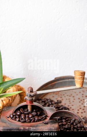 coffee beans inside an antique coffee grinder. embossed white wall with writing area. vertical photograph. Stock Photo