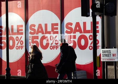 People walk past sales logos near Oxford Street in London, on Boxing Day. Stock Photo