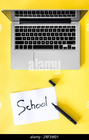 Laptop and a piece of paper with the inscription School, top view. Stock Photo