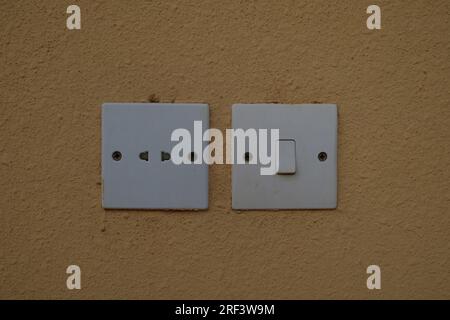 Electric Plug and Electric Switch on Dark Yellow Painted Wall Stock Photo