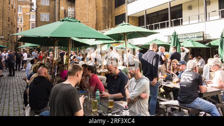 People socialising outside the ancient galleried George Inn, off Borough High Street, Southwark, London, England, U.K. Stock Photo