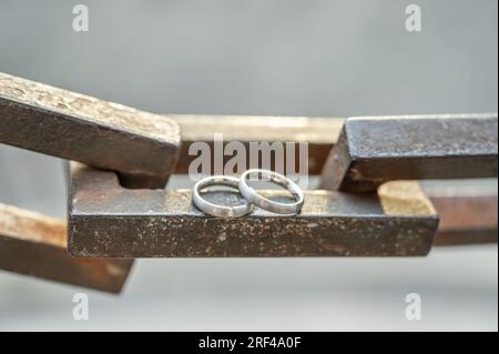 Two hands with wedding rings rest on a strong anchor chain. Stock Photo