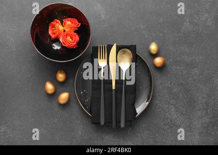 Table setting with Easter eggs and roses on dark background Stock Photo