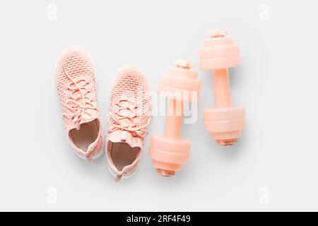 Pair of sneakers and dumbbells on white background Stock Photo