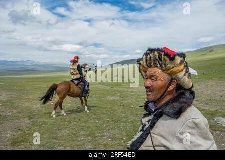 The Kazakh Eagle Hunter Dalaikhan (foreground) and his son on horseback holding a golden eagle at his summer camp in a remote valley in the Altai Moun Stock Photo