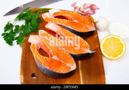 Fresh sliced salmon on wooden cutting board, over white background Stock Photo