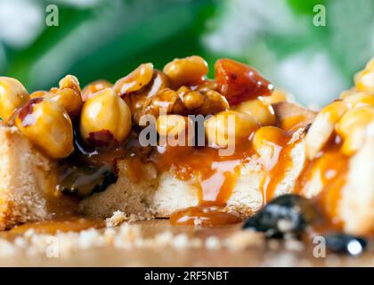 the ingredients used in the tartlet are hazelnuts, peanuts, dried apricots, dried plums, walnuts, round shaped tartlet with nuts and dried fruits pour Stock Photo