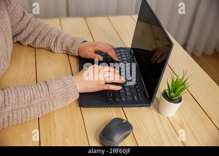 Young woman working on laptop. Female hands typing on pc keyboard. Stock Photo