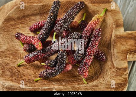 Afghan mulberry black and red on wooden scoop on gray wooden background Stock Photo