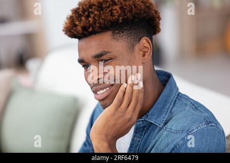 image of young african man sitting on sofa Stock Photo
