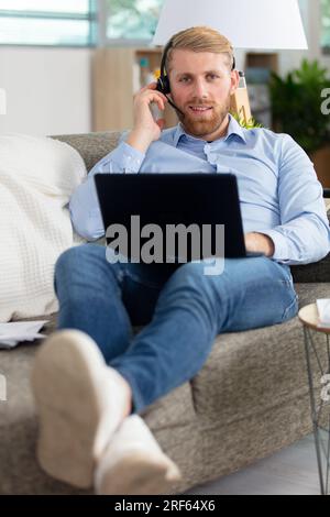 man on couch at home studying using laptop Stock Photo