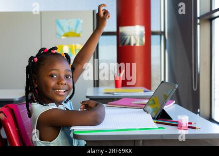 Happy african american schoolgirl having tablet video call in classroom ...