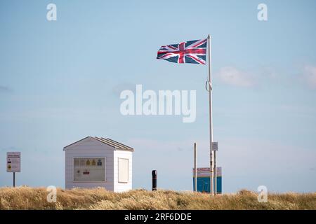 a beach hut and union flag on Worthing Beach on a windy day in summer Stock Photo