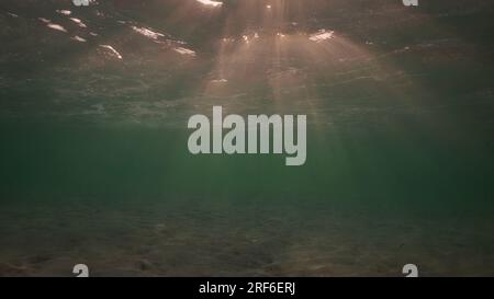 Low angle wide shot sun rays penetrating surface of water in the morning time, Underwater light creates beautiful veil, consisting of sunlight in the Stock Photo