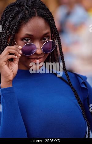 Portrait of beautiful african american woman with dreadlocks and sunglasses looking at camera Stock Photo