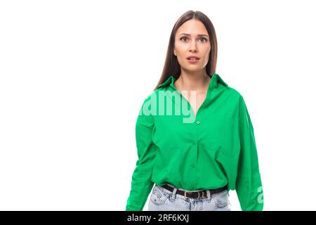 emotional young brown-eyed brown-haired woman with a bright facial expression in a green blouse on a white background with copy space Stock Photo